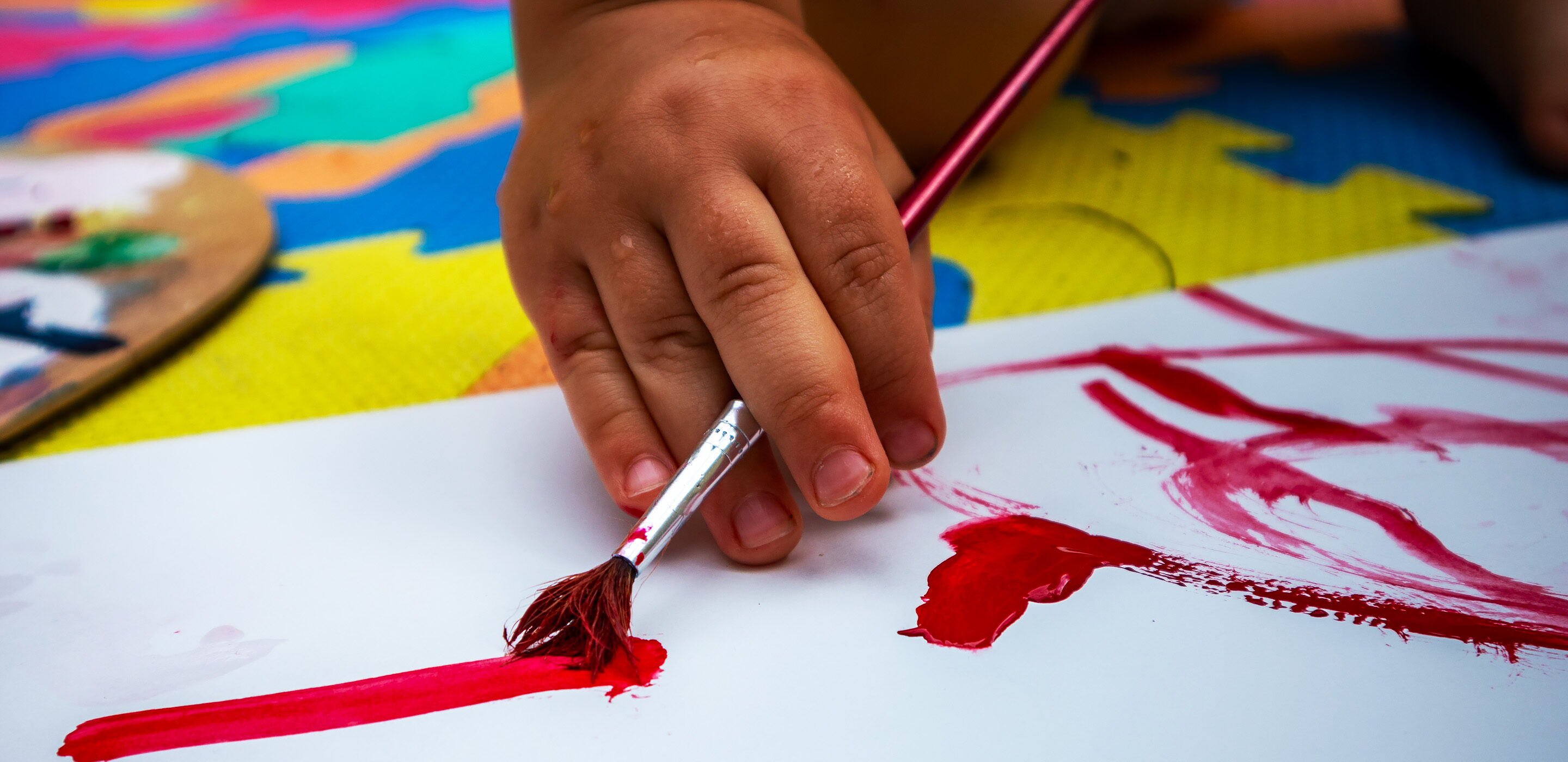 Ett barn målar med röd färg